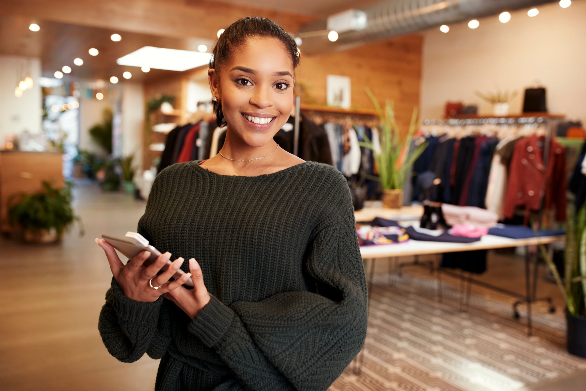 Young Hispanic woman smiling to camera in a clothes shop